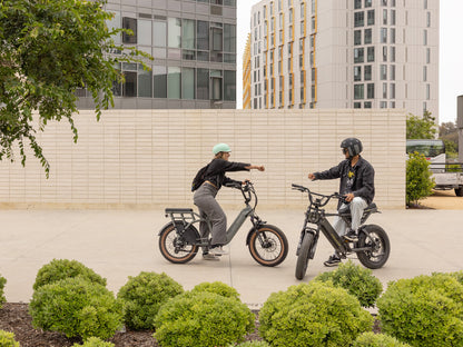 Troxus Lynx 2-Up electric bike rider meeting a friend in an urban setting, featuring step-thru frame and integrated rear passenger seat