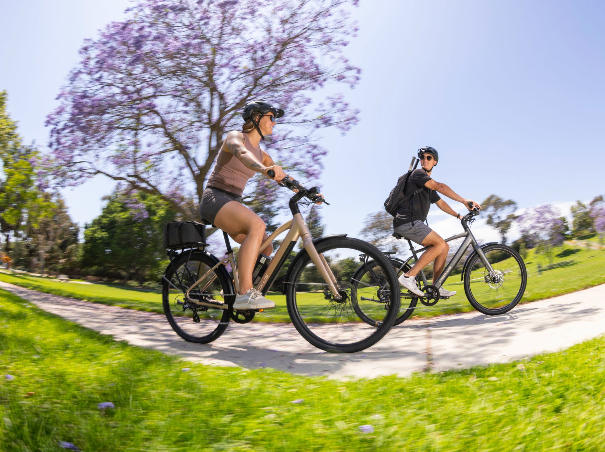 Troxus Trax Sport commuter electric bikes in use by riders on a paved park trail